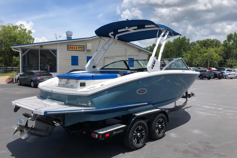 Slide: The Image of 2021 Cobalt CS22 boat on trailer, parked near a deli under a cloudy sky. - 5