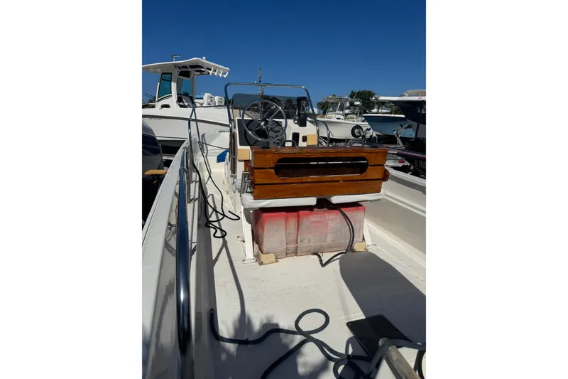 Slide: The Image of 1988 Boston Whaler 170 Montauk boat with wooden console, docked under clear blue sky. - 8