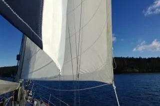 Slide: The Image of Person steering 1981 Ta-Shing Panda 40 sailboat on a calm lake. - 2
