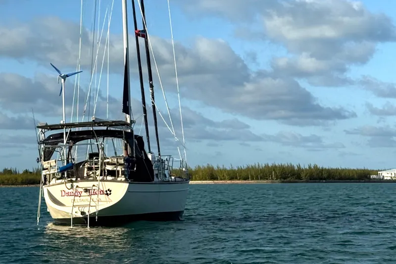 Slide: The Image of Sailboat Island Packet 380 (2002) anchored on calm water under a partly cloudy sky. - 10