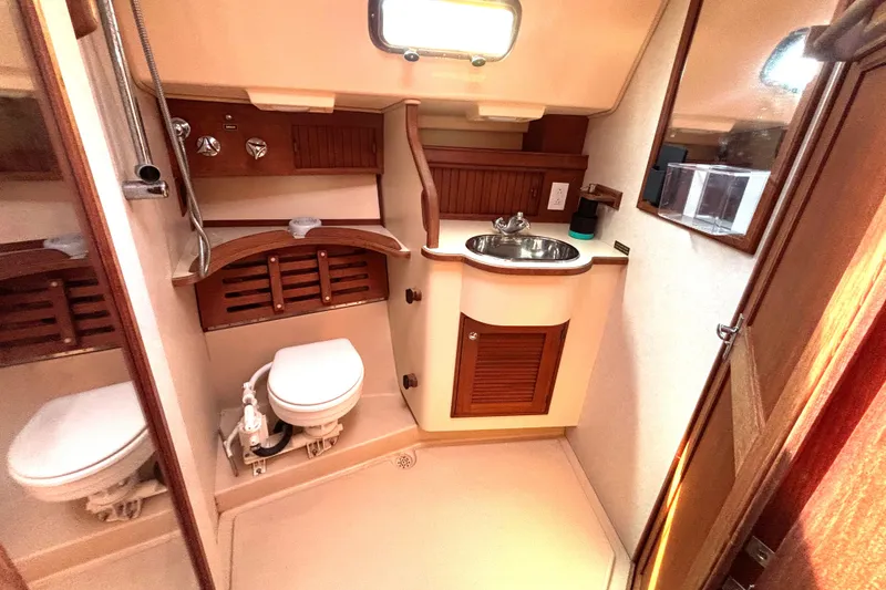 Slide: The Image of 2002 Island Packet 380 yacht bathroom with sink, toilet, and wooden cabinetry. - 24