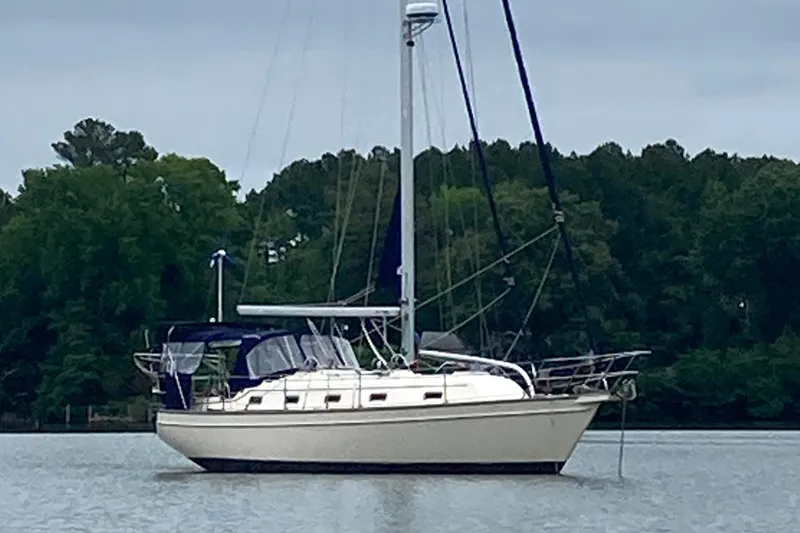 Slide: The Image of Island Packet 380 sailboat from 2002 anchored on a calm lake with forested background. - 5