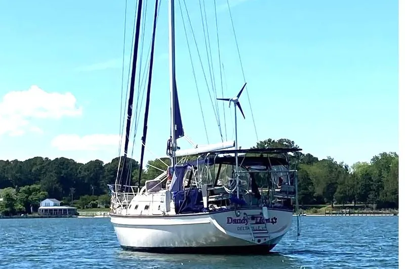 Slide: The Image of Sailboat Island Packet 380, 2002 model, anchored on a sunny day near a wooded shoreline. - 6