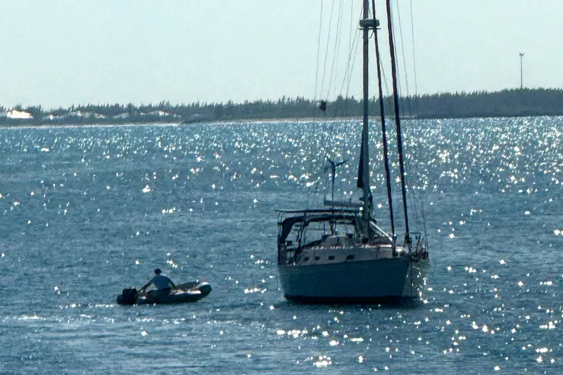 Slide: The Image of Sailboat Island Packet 380 (2002) on sparkling water with a small dinghy nearby. - 7