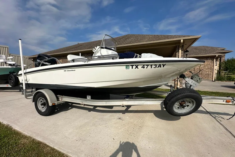 The Image of 2008 Boston Whaler 180 Dauntless boat on trailer, parked in driveway under blue sky. - 0