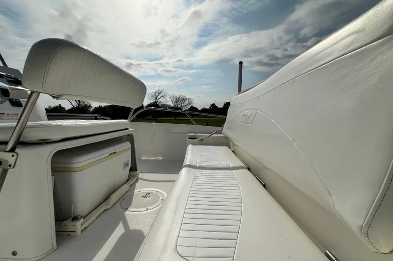 Slide: The Image of 2008 Boston Whaler 180 Dauntless boat interior with white seating and storage under a cloudy sky. - 21
