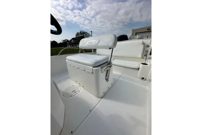 Slide: The Image of 2008 Boston Whaler 180 Dauntless boat interior with cushioned seating under a cloudy sky. - 22
