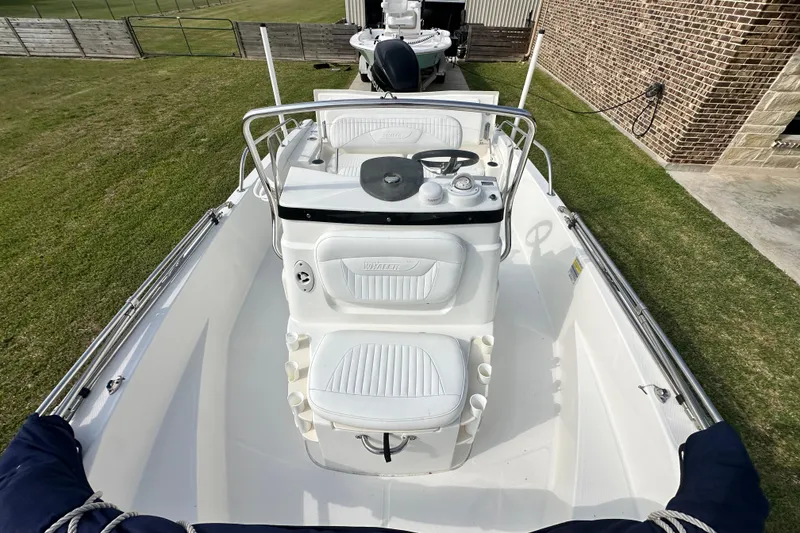 Slide: The Image of 2008 Boston Whaler 180 Dauntless boat with white seating and steering console, parked on grass. - 24