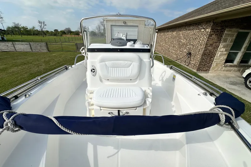 Slide: The Image of 2008 Boston Whaler 180 Dauntless boat with white seating and console, docked near a brick building. - 27