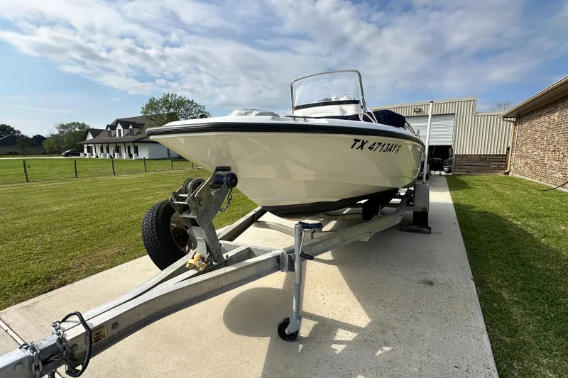 Slide: The Image of 2008 Boston Whaler 180 Dauntless boat on trailer, parked in driveway under cloudy sky. - 3