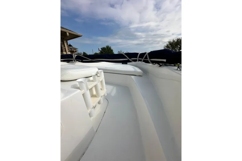 Slide: The Image of 2008 Boston Whaler 180 Dauntless boat deck with rod holders under a cloudy sky. - 33