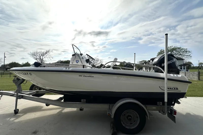 Slide: The Image of 2008 Boston Whaler 180 Dauntless boat on trailer under cloudy sky. - 6