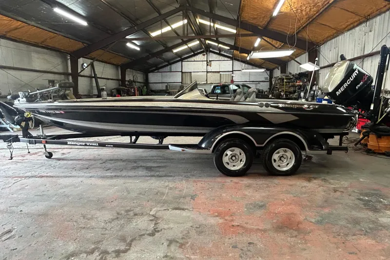 Slide: The Image of 2008 Ranger Z22 Comanche boat in a garage, featuring a sleek black design and dual-axle trailer. - 11