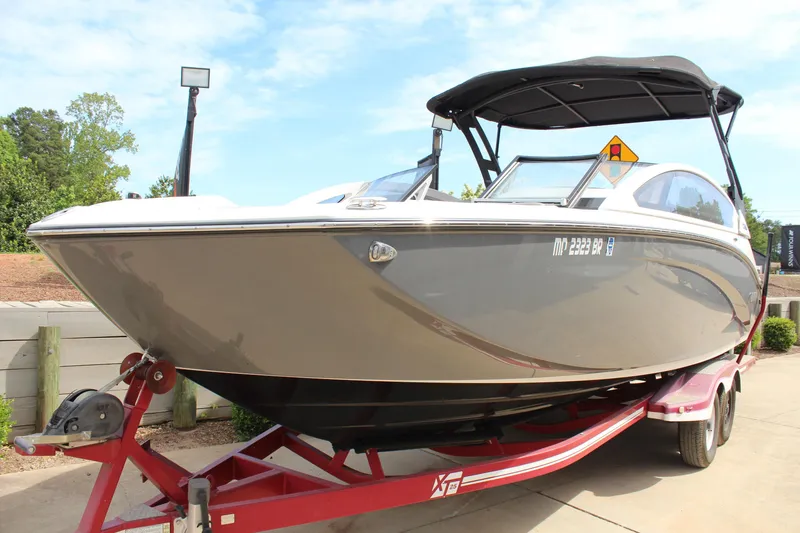 Slide: The Image of 2020 Yamaha Boats 275SE on trailer, sleek design, black canopy, parked outdoors. - 7