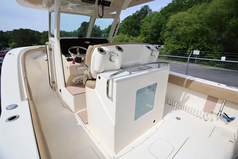 Slide: The Image of 2018 Scout 300 LXF boat interior with helm and seating, surrounded by lush greenery. - 16