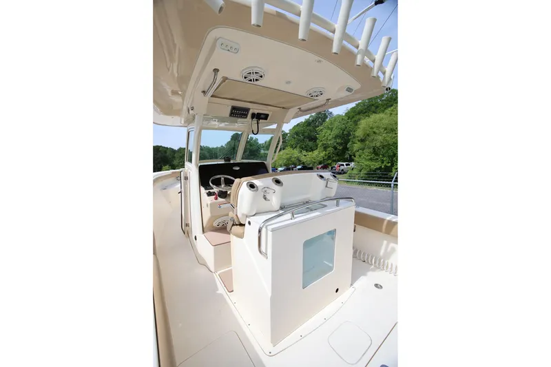 Slide: The Image of 2018 Scout 300 LXF boat interior with helm station and seating, surrounded by greenery. - 17
