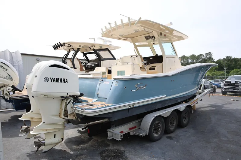 Slide: The Image of 2018 Scout 300 LXF boat with Yamaha engines on a trailer, parked outdoors. - 3