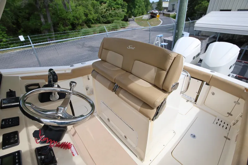 Slide: The Image of 2018 Scout 300 LXF boat helm with steering wheel and beige seating. - 35