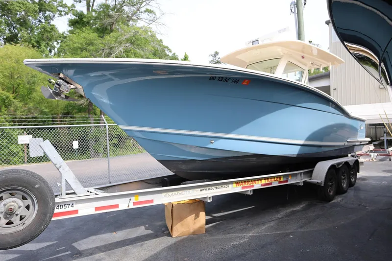 Slide: The Image of 2018 Scout 300 LXF boat on trailer, blue hull, parked outdoors. - 6