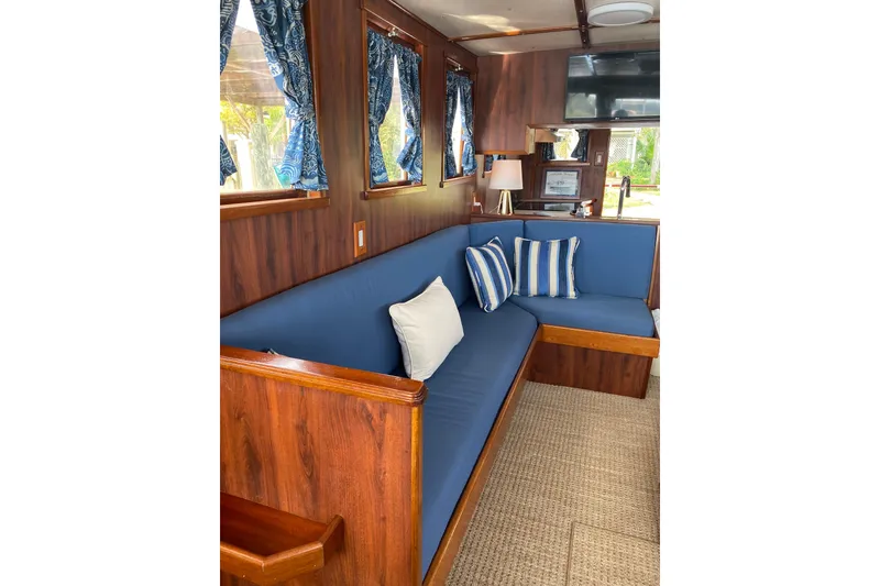 Slide: The Image of Interior of 1996 Bill Holland trawler with blue seating, striped pillows, and wooden accents. - 5
