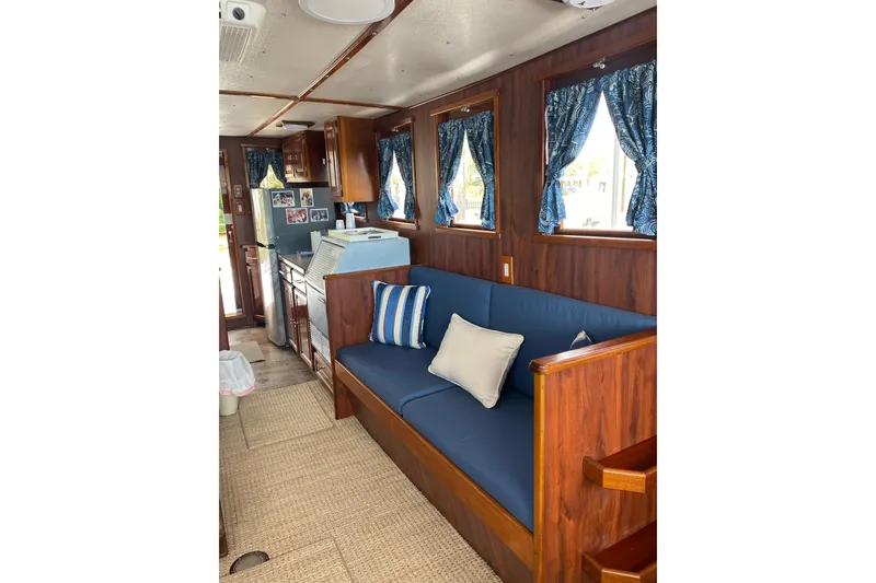 Slide: The Image of Interior of 1996 Bill Holland trawler with blue seating, wooden accents, and kitchen area. - 7