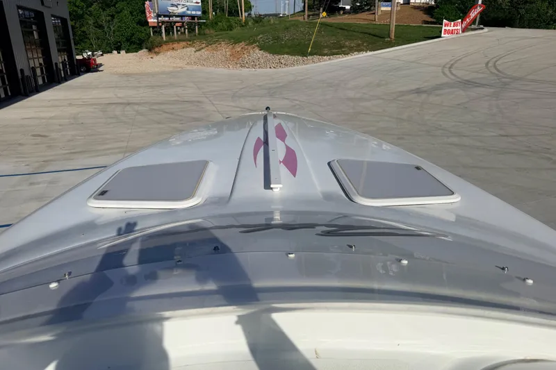 Slide: The Image of 1999 Baja 29 Outlaw boat on concrete, featuring sleek design and dual hatches. - 10