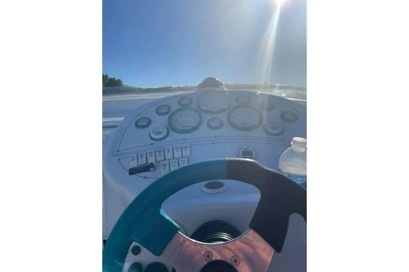 Slide: The Image of 1999 Baja 29 Outlaw boat dashboard with steering wheel and gauges under bright sunlight. - 22