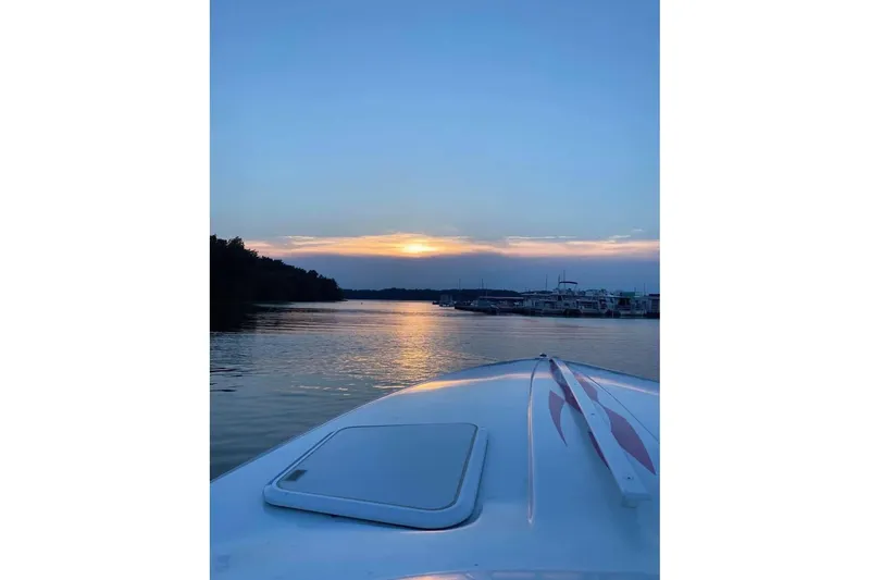 Slide: The Image of 1999 Baja 29 Outlaw boat cruising at sunset on a serene lake. - 23