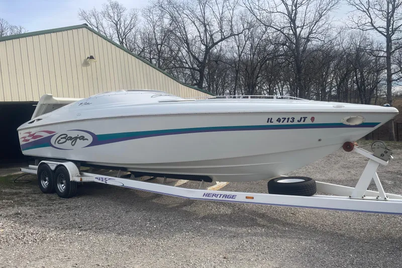 Slide: The Image of 1999 Baja 29 Outlaw speedboat on trailer, parked outdoors near a building. - 38
