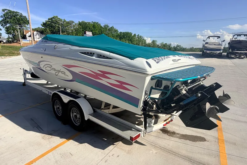 Slide: The Image of 1999 Baja 29 Outlaw speedboat on trailer, vibrant graphics, teal cover, parked outdoors. - 5