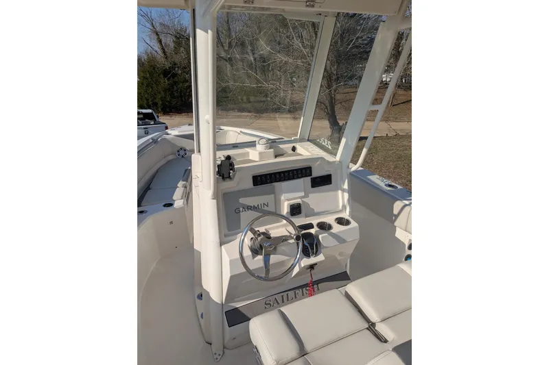 Slide: The Image of 2025 Sailfish 232 CC boat cockpit with Garmin navigation system and steering wheel. - 2