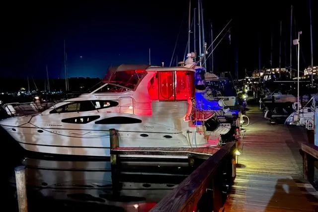 Slide: The Image of 2003 Cruisers Yachts 4050 Express docked at night with colorful lighting. - 3