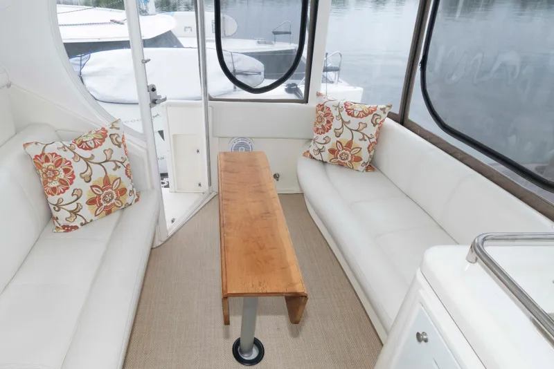 Slide: The Image of 2003 Cruisers Yachts 4050 Express interior with white seating, floral pillows, and wooden table. - 8