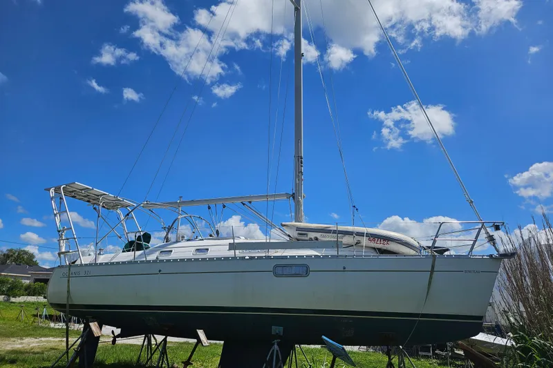 Slide: The Image of 1997 Beneteau Oceanis Clipper 321 sailboat deck with green cover, docked outdoors. - 13