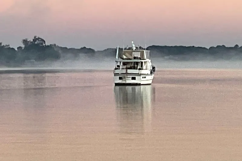 Slide: The Image of DeFever 44 Sundeck Trawler, 1998, cruising on calm waters at sunrise with misty background. - 11