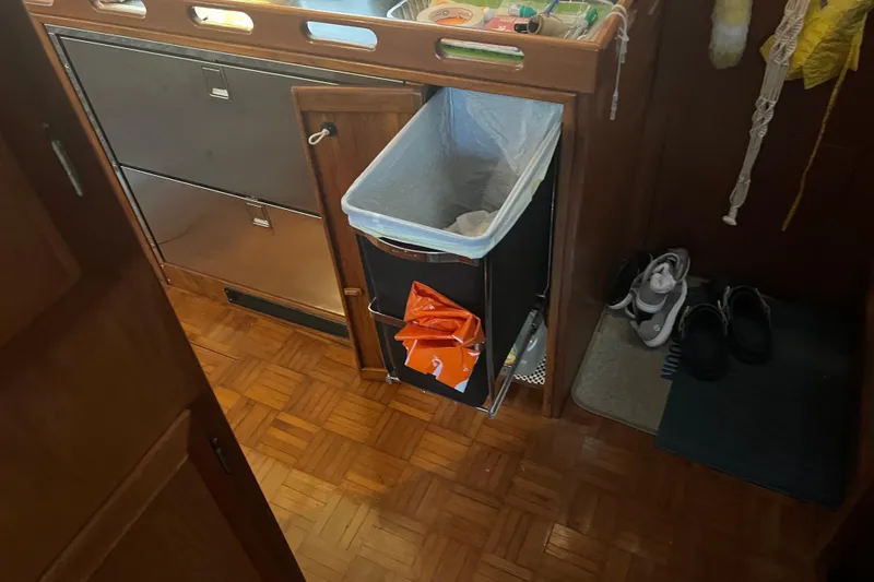 Slide: The Image of Interior of 1998 DeFever 44 Sundeck Trawler with trash bin and shoes on wooden floor. - 12