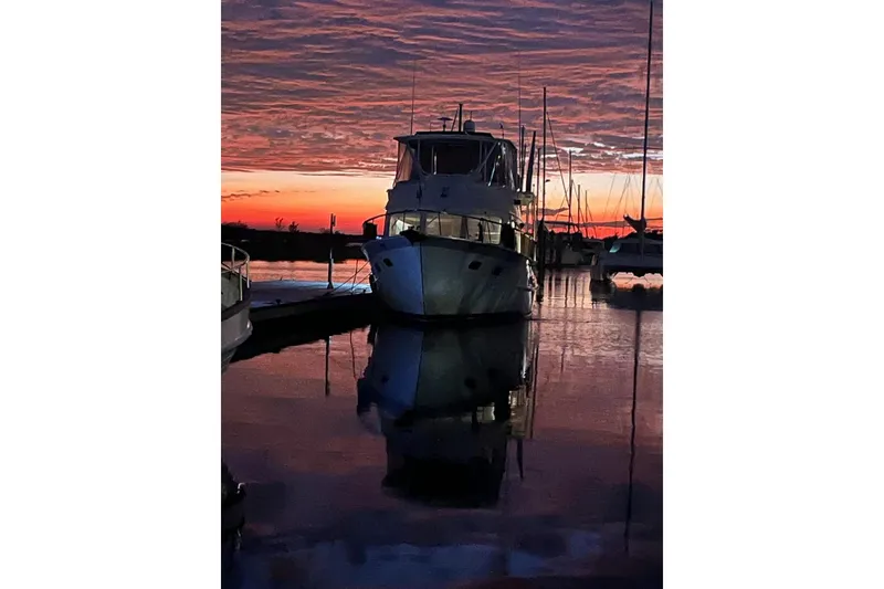 Slide: The Image of 1998 DeFever 44 Sundeck Trawler at sunset, reflecting on calm marina waters. - 14