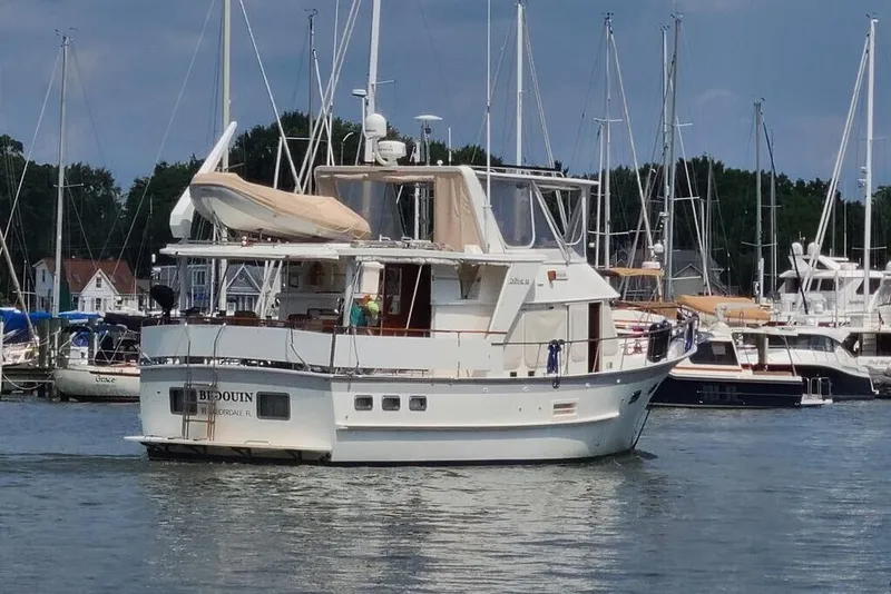 Slide: The Image of 1998 DeFever 44 Sundeck Trawler docked in a marina with sailboats. - 2