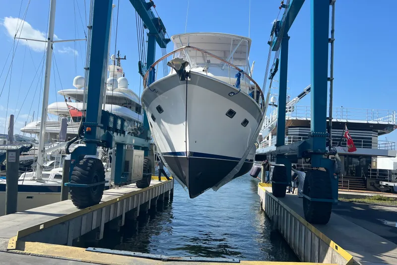 Slide: The Image of 1998 DeFever 44 Sundeck Trawler being lifted at a marina with blue skies. - 21