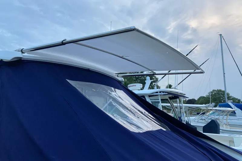 Slide: The Image of 2018 Cobalt R35 boat with blue canopy and extended sunshade at marina. - 31