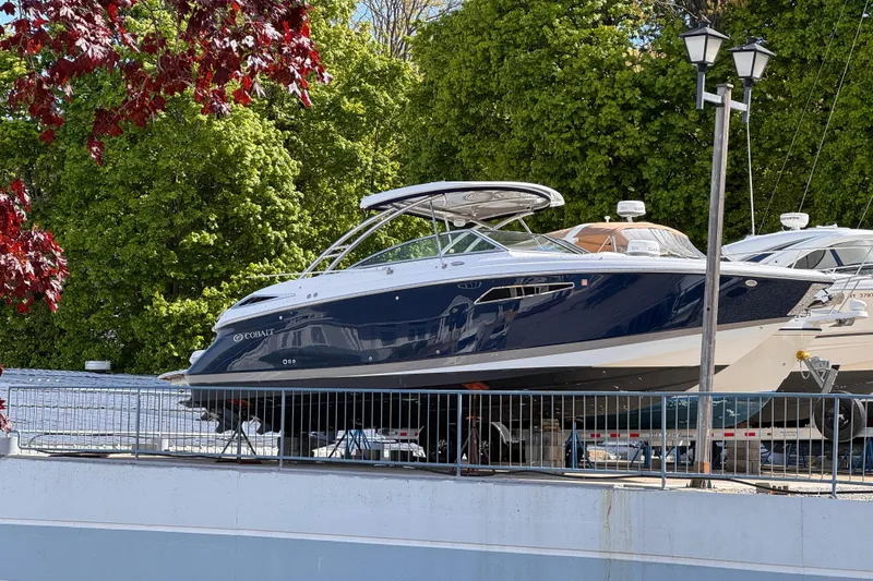 Slide: The Image of 2018 Cobalt R35 boat docked, surrounded by lush green trees and a clear sky. - 5