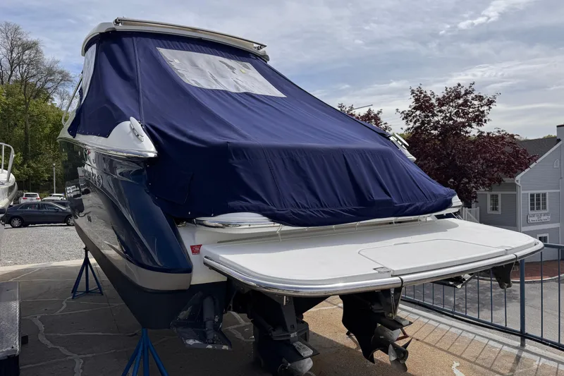 Slide: The Image of 2018 Cobalt R35 boat with blue cover on dry dock, surrounded by trees and buildings. - 51