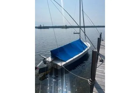 Slide: The Image of 2016 Flying Scot 19 sailboat docked with blue cover on calm water. - 2