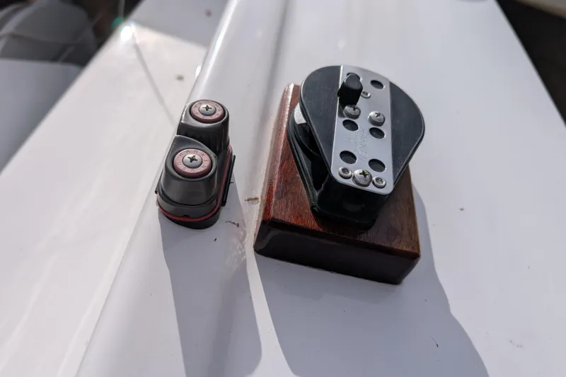 Slide: The Image of Close-up of a 2016 Flying Scot 19 sailboat deck hardware, featuring cleats and pulley. - 5