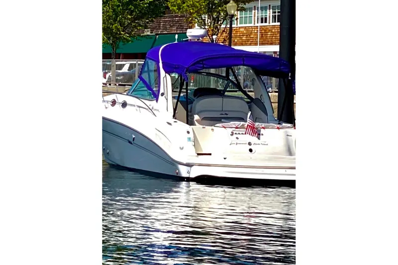 Slide: The Image of 2006 Sea Ray 300 Sundancer boat docked with blue canopy and American flag. - 2