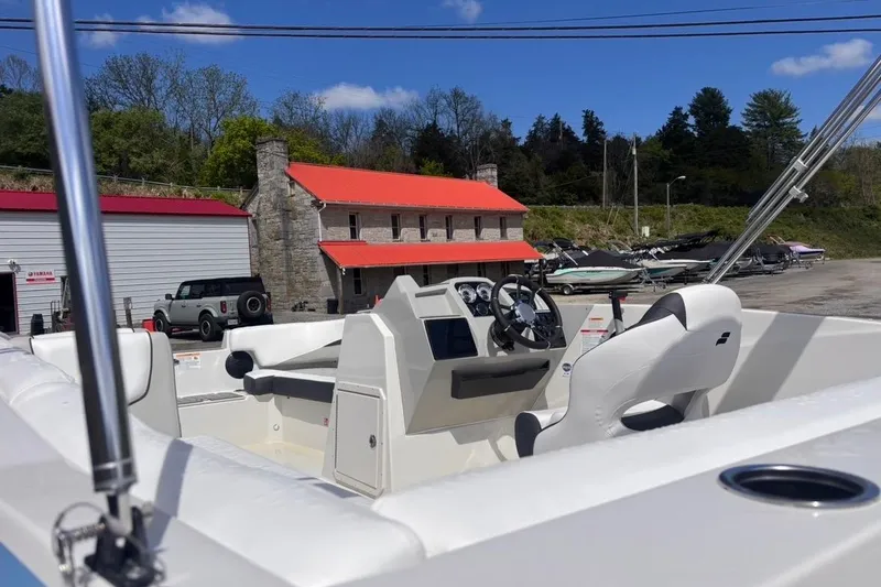 Slide: The Image of 2026 Starcraft SVX 191 OB boat interior with steering wheel, parked near rustic building. - 4