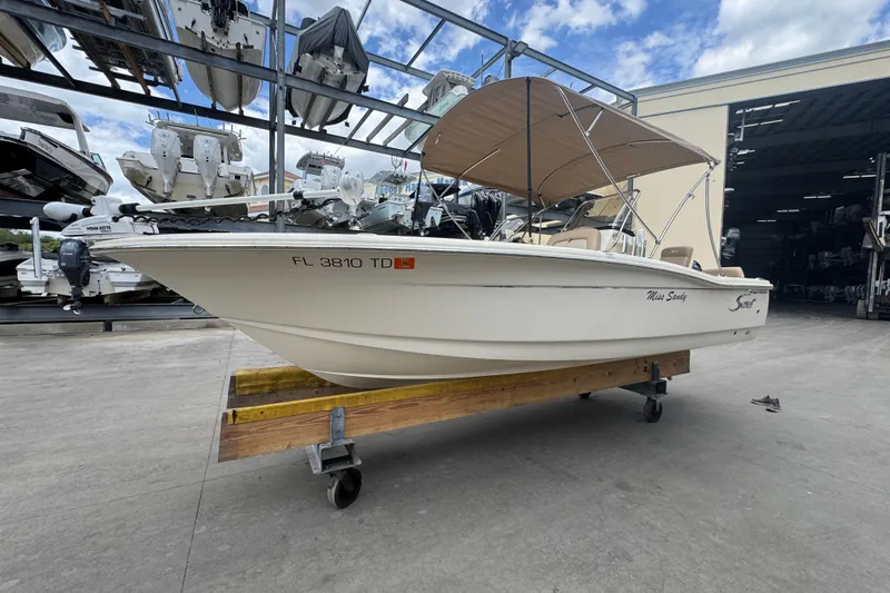 Slide: The Image of 2022 Scout 195 Sport Dorado boat with canopy on a trailer in a marina. - 2