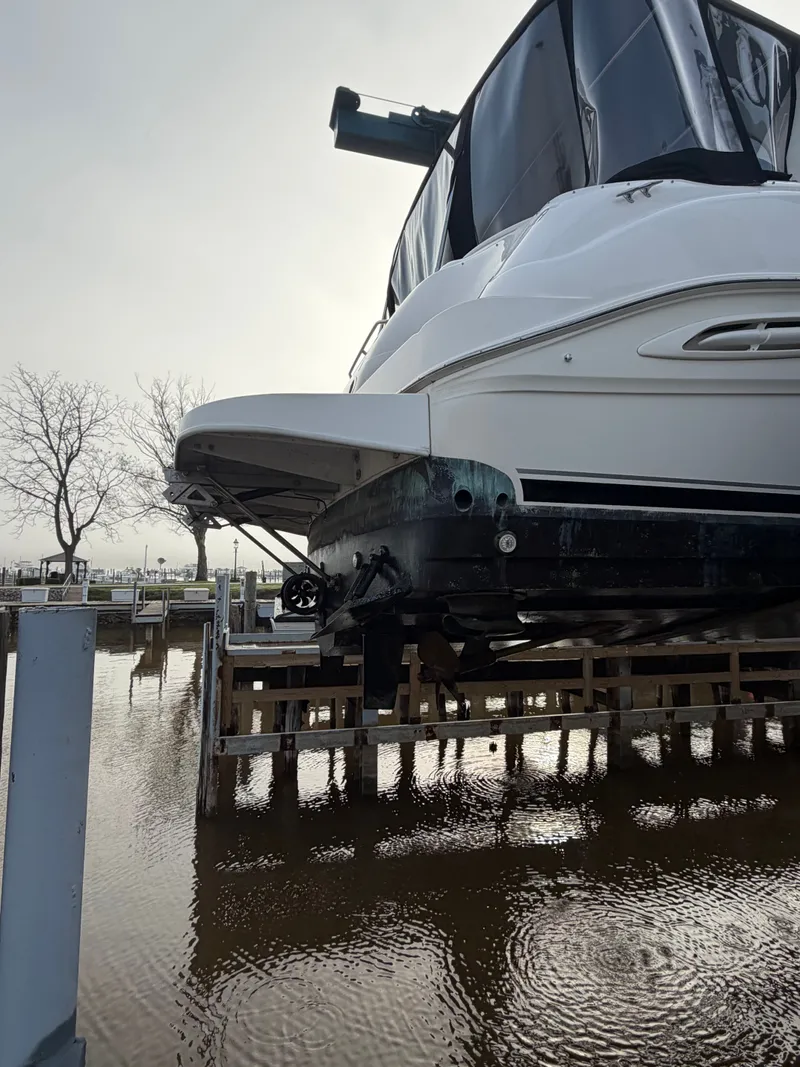 Slide: The Image of 1999 Sea Ray Sundancer 460 on a boat lift by the water. - 49