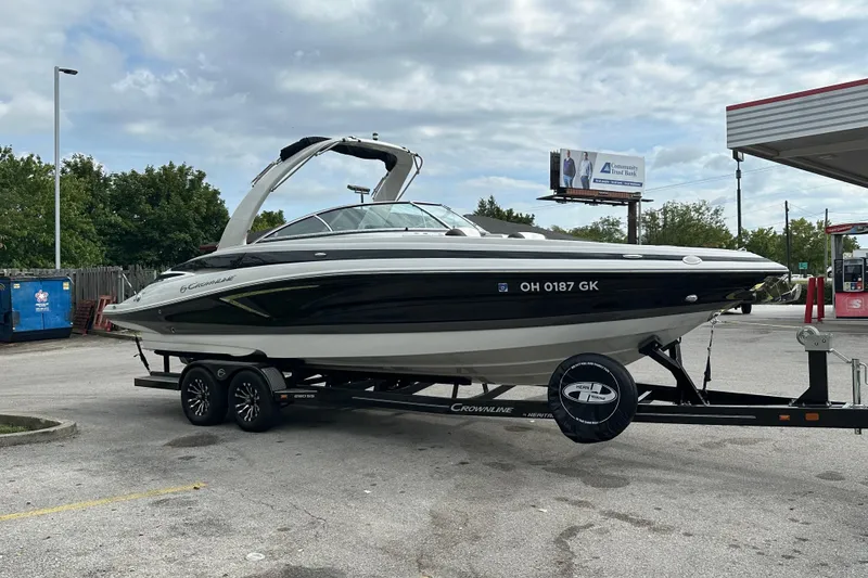 The Image of 2022 Crownline 280 SS boat on trailer at a gas station, under cloudy sky. - 1