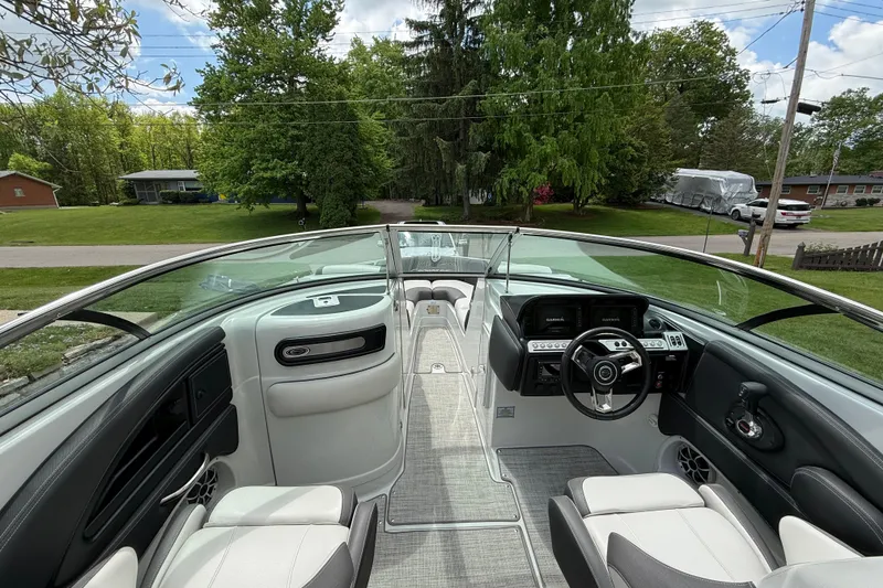 Slide: The Image of 2022 Crownline 280 SS boat interior with modern dashboard and seating, surrounded by lush greenery. - 11